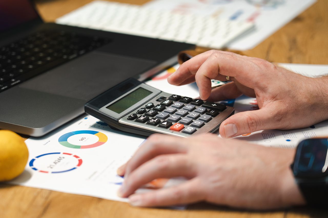 The Art of Drawing Readers In: Your attractive post title goes here A person analyzing financial data using a calculator and laptop on a desk.