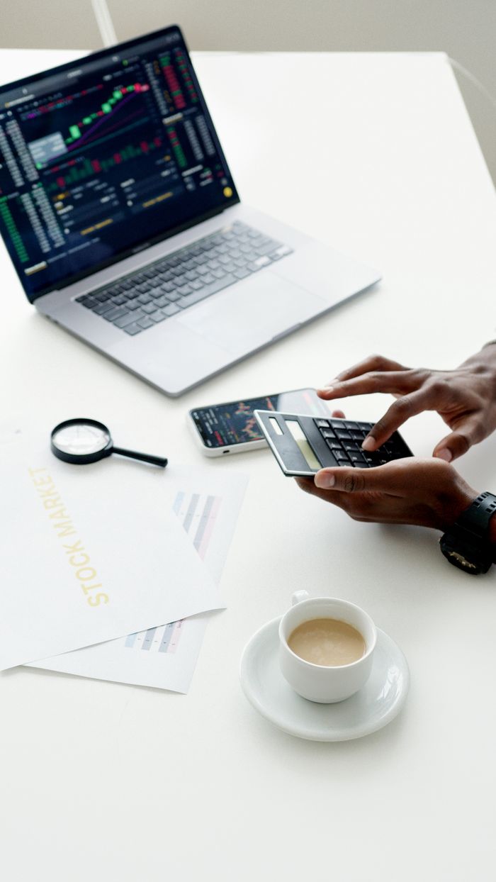 Mastering the First Impression: Your intriguing post title goes here A businessman using a laptop and smartphone to analyze stock market trends indoors.