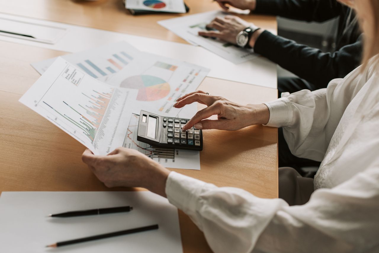 Crafting Captivating Headlines: Your awesome post title goes here Hands performing financial calculations with charts and a calculator at a meeting table.
