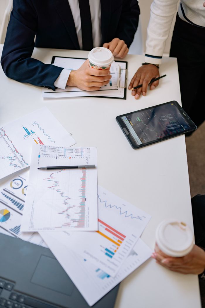 Crafting Captivating Headlines: Your awesome post title goes here High-angle view of office meeting with charts, coffee, and tablet device.